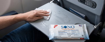 Person cleaning airplane tray table with SONO wipes