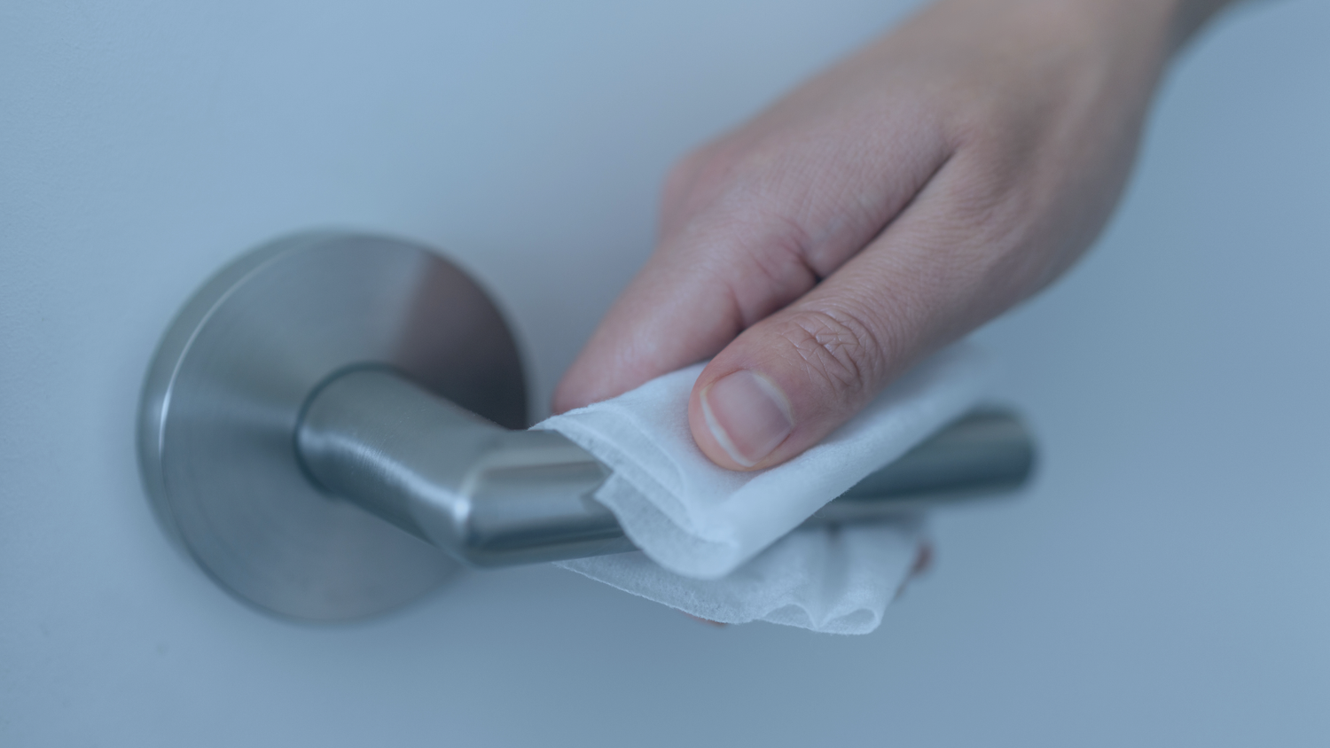 Hand cleaning a metallic door handle with a wipe
