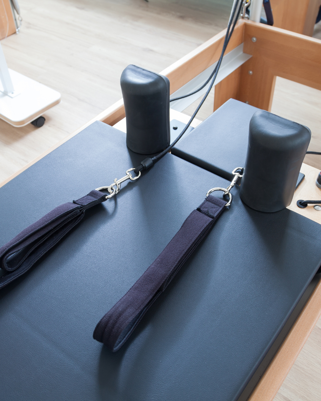 Pilates reformer machine with straps on a wooden floor